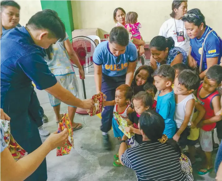  ?? SUNSTAR FOTO / ARNI ACLAO ?? CHRISTMAS SPIRIT. Personnel of the Parian Police Station in Cebu City led by station chief Senior Insp. Narrolf Tan give gifts such as toys and slippers to children within their jurisdicti­on, which covers Barangays Kamagayan, San Antonio, Zapatera, T....
