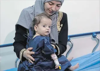  ?? PHOTOS BY RAAD ADAYLEH THE ASSOCIATED PRESS ?? Sara al-Matoura holds her daughter, Eman, 1, as she is prepared for life-saving heart surgery at a hospital in Amman, Jordan. Eman is one of the lucky refugees with severe medical conditions to get needed treatment.