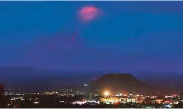  ??  ?? PUNCAK Gunung Mayon bercahaya ketika diliputi kabus yang dirakam dari bandar Legazpi di wilayah Albay pada awal pagi semalam. - AFP