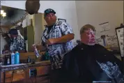  ??  ?? Barber Ted Lewis cuts Scott Mcdonald’s hair in Alturas. The town was the first in the state to reopen from the shelter-in-place orders two and a half months ago. Residents say social distancing is a way of life.