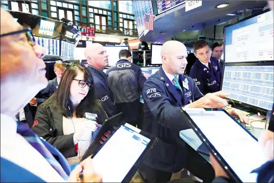  ??  ?? Specialist Mario Picone, (right), works with traders at his post on the floor of the New York Stock Exchange. (AP)