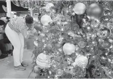  ?? SETH WENIG, THE ASSOCIATED PRESS ?? Christmas tree receives finishing touches: Prices are going up due to limited supplies.