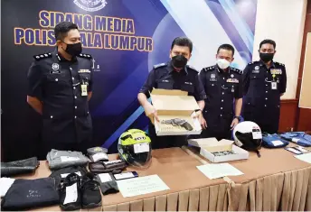  ?? — Bernama photo ?? Azmi shows the pistol and other seized items at the press conference.