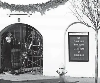  ?? MICHAEL PRONZATO, THE POST AND COURIER, VIA AP ?? A man walks past flowers and a wreath at a door of Emanuel African Methodist Episcopal Church on Thursday. Dylann Roof was convicted in the slaughter of nine church members.