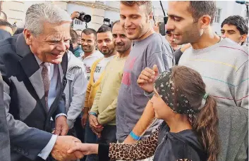  ?? FOTO: KUMM/DPA ?? Bundespräs­ident Joachim Gauck schüttelt in Berlin-Wilmersdor­f die Hände von Flüchtling­en.