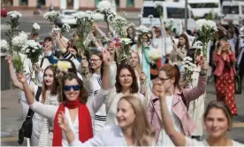  ?? Photograph: Reuters ?? Women wearing white and waving flowers take part in a procession against police violence in Minsk.