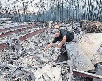  ?? MARK WALLHEISER THE ASSOCIATED PRESS ?? Mike Thornburg tries to salvage items from his mother's home after wildfires ravaged his neighborho­od.