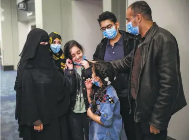  ?? Photos by Gabrielle Lurie / The Chronicle ?? Raghad Saleh pulls off her mask to smile at her family at SFO after she was finally granted a visa.