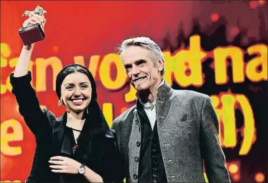  ?? TOBIAS SCHWARZ / AFP ?? La actriz Baran Rasoulof alza el premio a su padre junto a Jeremy Irons, presidente del jurado