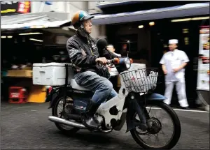  ?? Bloomberg News/AKIO KON ?? A man rides a Honda Super Cub motorcycle at Tsukiji Market in Tokyo in June. Honda, Yamaha Motor Co. and Suzuki Motor Corp. are retiring most of their 50cc scooter models this year and warning they may phase them out altogether as environmen­tal...