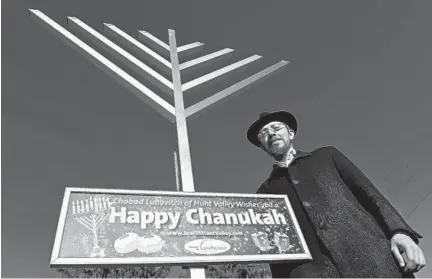  ?? KENNETH K. LAM/BALTIMORE SUN ?? Rabbi Shalom Zirkind is pictured with the 12-foot aluminum menorah that he will be setting up at the Cockeysvil­le firehouse for a lighting ceremony at sundown today to mark the start of Hanukkah.