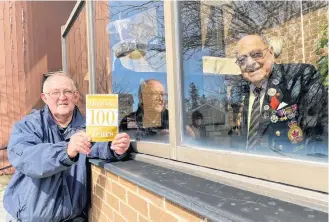  ??  ?? Don McCumber holds a birthday card at the window of Veterans Place to wish veteran Alcide LeBlanc a happy 100th birthday.