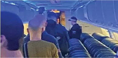  ?? ?? Police escort: Tenerife-bound passengers are led off a TUI flight by officers at Manchester