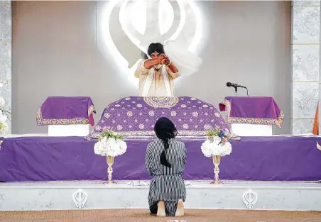  ?? Photos by Elizabeth Conley / Staff photograph­er ?? A member of Sikh Center of the Gulf Coast Area kneels before the Granth, Sikhism’s holy book, in the gurdwara in Houston.