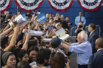  ?? DAMIAN DOVARGANES — THE ASSOCIATED PRESS ?? Democratic presidenti­al candidate Sen. Bernie Sanders, I-Vt., signs autographs in Santa Ana on Friday.