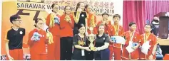  ??  ?? The representa­tive of SMK Kuching High receives the championsh­ip trophy from tournament director Ling Ung Hee (right).