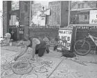  ?? MICHAEL SEARS / MILWAUKEE JOURNAL SENTINEL ?? Artist Wisdom Prometheus Grey chalks out a memorial to Bernell Trammell, who was shot and killed outside this building at 915 E. Wright St. in Milwaukee known as eXpression­s Journal. Flowers, candles and a teddy bear were also left at the door.