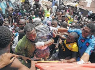  ?? Sunday Alamba / Associated Press ?? A child is rescued Wednesday from the rubble of a school building in Lagos, Nigeria. Anguished families awaited word as crews worked to pull victims out of the ruins before night fell.