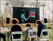  ?? (The New York Times/Evan Jenkins) ?? Fans of Bob Ross try their hands at re-creating “Sunset Aglow” from a 1993 episode of “The Joy of Painting,” screened on the lawn near his former studio during the opening of the “Bob Ross Experience” at the Minnetrist­a museum in Muncie, Ind.