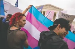  ?? ANNA MONEYMAKER/THE NEW YORK TIMES ?? Demonstrat­ors hold up a transgende­r flag Oct. 8, 2019, outside the Supreme Court in Washington. About 1.6 million people in the United States are transgende­r, and 43% of them are young adults or teenagers, according to a new report providing the most recent national estimates of this population.