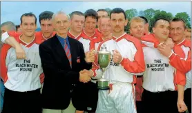  ?? (Pic: The Avondhu Archives) ?? Paddy Pollard, chairman Red House League, presenting the Liam Fitzgerald Cup in 2002 to Cappoquin captain, Micheal Walsh, in the presence of delighted team mates.