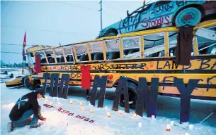  ?? JOHN RENNISON THE HAMILTON SPECTATOR ?? Skyler Williams places candles in front of the bus barricade on Argyle Street following a candle light vigil Sunday. The red dress is the symbol of the missing and murdered women and girls.