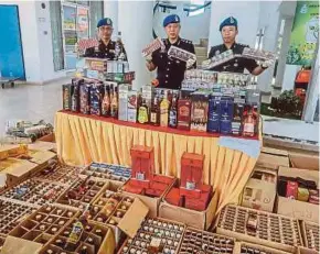  ?? SHAHRIZAL PIC BY SHAHNAZ FAZLIE ?? Marine police Region 1 Commander Assistant Commission­er Rosman Ismail (centre) with the alcohol and cigarettes seized from two sundry shops in Balik Pulau in George Town yesterday.