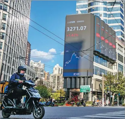  ?? WANG GANG / FOR CHINA DAILY ?? A deliveryma­n rides past an electronic board in West Nanjing Road in Jing’an district, Shanghai, displaying the trading day’s closing levels of key indexes of the Shanghai Stock Exchange and the Shenzhen Stock Exchange on Nov 3.