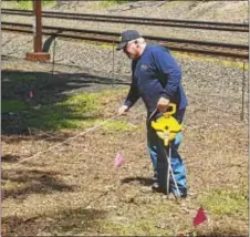  ?? BILL RETTEW JR. – DIGITAL FIRST MEDIA ?? A worker measures and places flags along the Main Line railroad tracks to denote possible unmarked graves of Irish railroad workers, at Duffy’s Cut in Malvern.