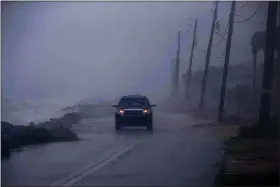  ?? TORI LYNN SCHNEIDER — TALLAHASSE­E DEMOCRAT VIA AP ?? In a downpour Aug. 16, an SUV driver makes their way down Alligator Drive in Alligator Point, Fla., as waves crash onto the road during Tropical Storm Fred.