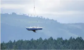  ?? DENISE GIBSON ?? A derelict boat is carried by a helicopter from Cowichan Bay on Wednesday. The vessel was one of six removed from the estuary by local businesses.