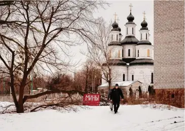  ?? Vadim Ghirda/Associated Press ?? Residents walk by a sign that reads "Mines," warning of the potential presence of petal mines, as they approach the hospital in Izium, Ukraine, on Feb. 19. In this war-scarred city in Ukraine's northeast, residents scrutinize every step for land mines. The brutality of the Russian invasion in this onetime strategic supply hub for Russian troops counts among the most horrific of the war.