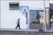  ?? OSCAR RODRIGUEZ ZAPATA VIA AP ?? A man walks next to a partially-covered Virgin of Guadalupe mural in Los Angeles in 2018. January 2023marked 10years since Zapata began documentin­g images of Guadalupe, at first on his phone for his own pleasure, but eventually taking his hobby more seriously, particular­ly as he noticed more and more Guadalupe images were vanishing.