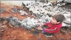  ?? (AP) ?? A Syrian boy warms his hands on a burning wreckage of a government military helicopter that was shot down in the countrysid­e, west of the city of Aleppo, on Feb 14.