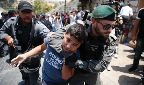  ?? AHMAD GHARABLIAH­MAD/AFP/GETTY IMAGES ?? Israeli border guards detain a Palestinia­n youth during a demonstrat­ion outside the Lions Gate, a main entrance to the Al-Aqsa Mosque compound.