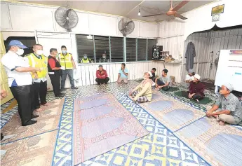  ??  ?? JHEAINS Sandakan administra­tion officer Romzi Abdul Rahman (le ) and Sandakan Police Chief Mohd Azhar Hamin (second le ) at Surau Al-Munawarah Kampung Mangkalina­u where 11 people were detained for violating the Movement Control order.