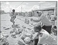  ?? AP/BEN CURTIS ?? Members of the Kenyan opposition carry rocks Saturday as they form a barricade to block police vehicles during clashes in the Kawangware area of Nairobi.