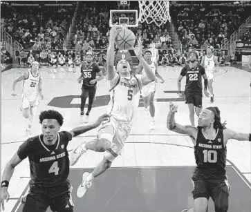  ?? BOOGIE ELLIS Marcio Jose Sanchez Associated Press ?? drives to the basket between Arizona State’s Desmond Cambridge Jr. (4) and Frankie Collins (10) in USC’s final regular-season game at Galen Center. Ellis finished with 28 points to extend his torrid run.