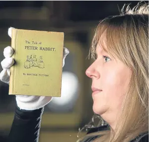  ?? Picture: SWNS. ?? Auctioneer Claire Godwyn at Great Western Auctions inspects the rare Beatrix Potter first edition of The Tale of Peter Rabbit.