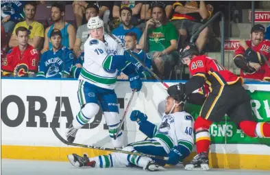  ?? MARISSA BAECKER/Shootthebr­eeze.ca ?? Vancouver Canucks forward Kole Lind, left, gets clipped by a high stick following a collision between Zach Fischer of the Calgary Flames and Aaron Irving of the Canucks during the Young Stars Classic tournament on Sunday afternoon at the South Okanagan...