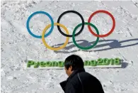  ?? AP ?? A man walks by the Olympic rings with a sign of 2018 Pyeongchan­g Olympic and Paralympic Winter Games. —