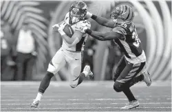  ?? AP Photo/Bryan Woolston ?? ■ Denver Broncos running back Phillip Lindsay (30) is tackled by Cincinnati Bengals strong safety Shawn Williams (36) during the first half Sunday in Cincinnati. A terrific trio of rookies, including Lindsay, has led a turnaround from a 3-6 start to help Denver win three straight and get into playoff contention.