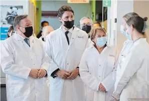  ?? GRAHAM HUGHES THE CANADIAN PRESS ?? Quebec Premier François Legault, left, and Prime Minister Justin Trudeau tour a research lab at Mcgill University prior to an announceme­nt of the opening of a Moderna vaccine production and research facility in Montreal on Friday.