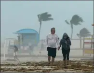  ?? (AP/Wilfredo Lee) ?? A couple walk through a downpour Sunday in Miami Beach, Fla., as Tropical Storm Eta draws closer. More photos at arkansason­line.com/119eta/.