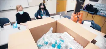  ?? BEN GARVER/THE BERKSHIRE EAGLE FILE ?? Nurse Carisa Vincent and Hope Rose Kelly prepare pool tests for COVID-19 behind a mountain of supplies at Reid Middle School in Pittsfield, Mass.