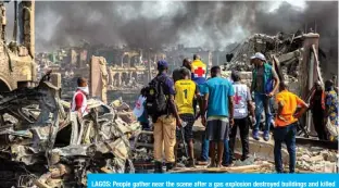  ??  ?? LAGOS: People gather near the scene after a gas explosion destroyed buildings and killed at least 17 people, in Nigeria’s commercial capital Lagos on March 15, 2020.— AFP