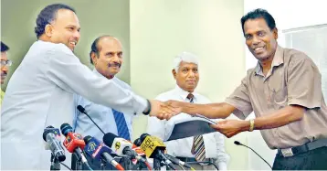  ??  ?? Minister Navin Dissanayak­e hands over a copy of the report to Lankadeepa’s senior sports journalist Namal Pathirage.