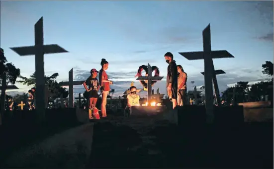  ?? BRUNO KELLY / REUTERS ?? Familiars d’un home mort per covid visiten la seva tomba en un cementiri de la ciutat brasilera de Manaus