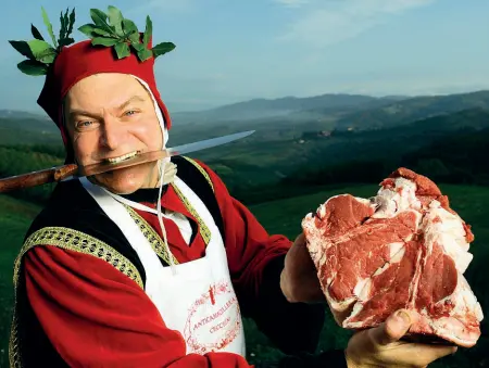  ??  ?? Dario Cecchini, il macellaio poeta di Panzano, travestito da Dante esibisce una bistecca