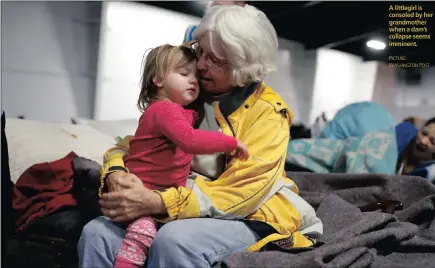  ??  ?? A littlegirl is consoled by her grandmothe­r when a dam’s collapse seems imminent.